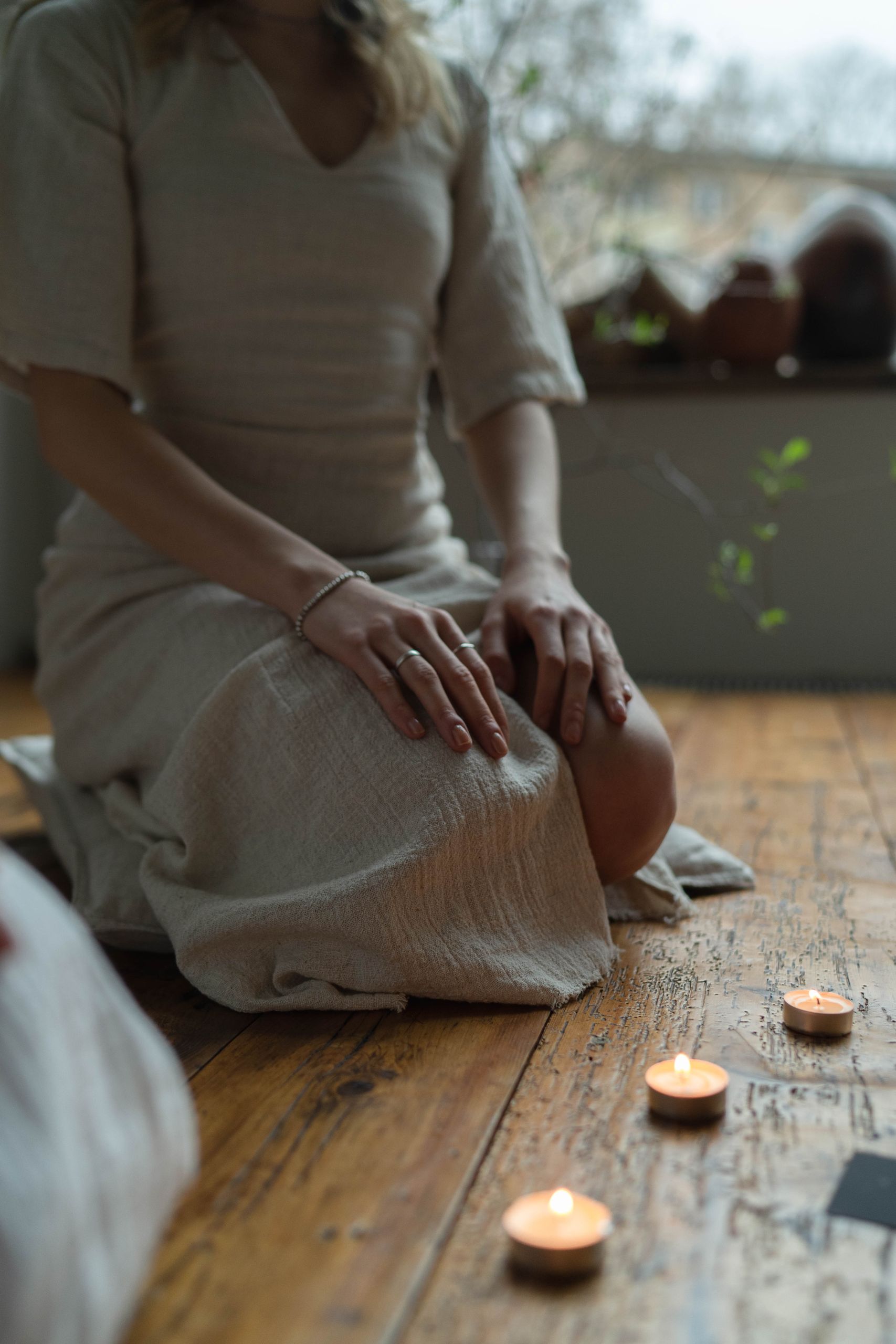 A serene scene of a woman sitting with lit candles, embodying peace and tranquility.